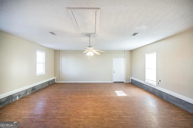 an empty room with windows and chandelier fan
