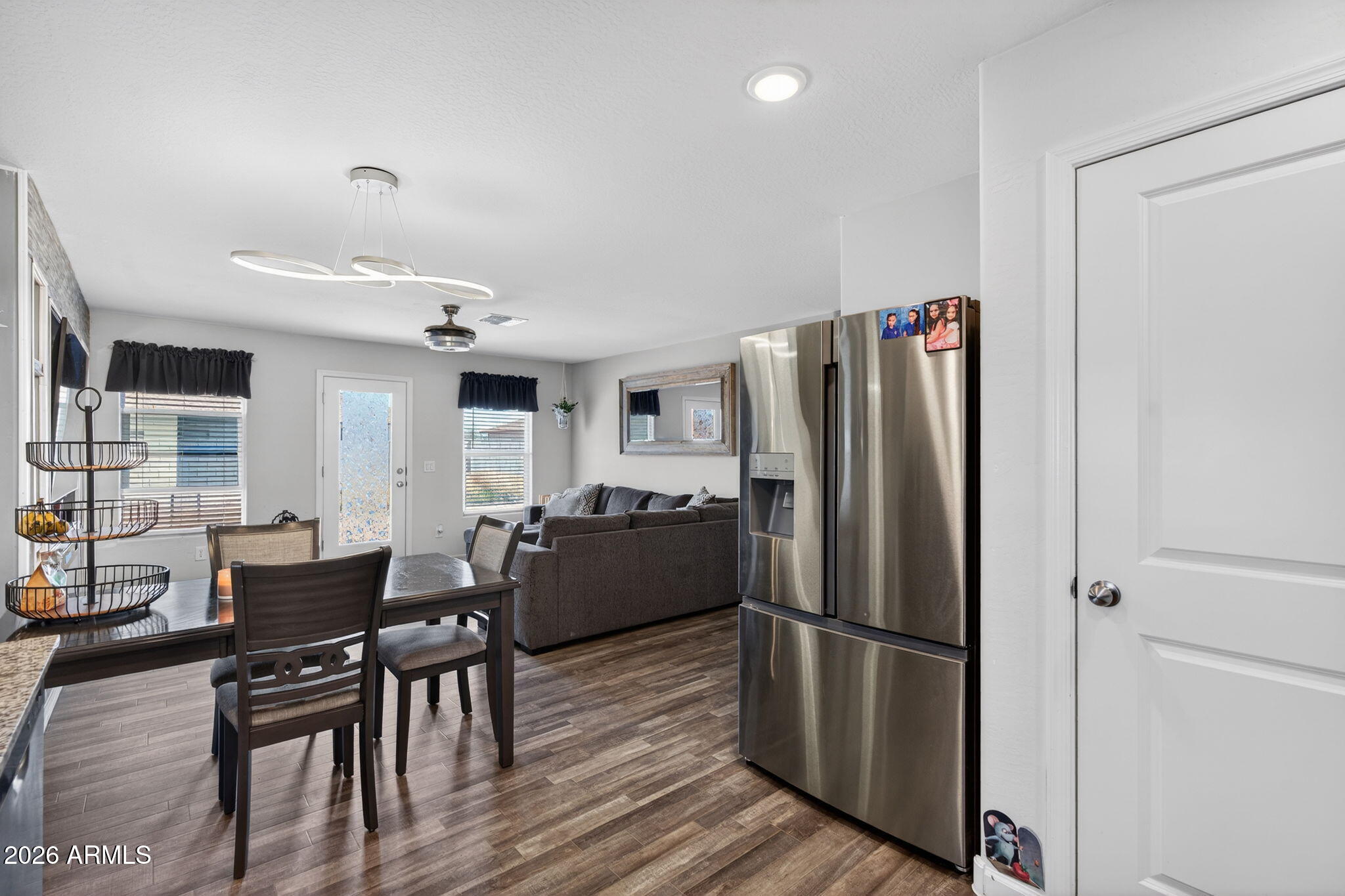14423 South Capistrano Road Arizona City, AZ 85123 - Photo 13 of 36 a kitchen with stainless steel appliances a refrigerator a stove a dining table and chairs with wooden floor