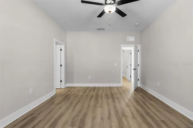 an empty room with wooden floor fan and window