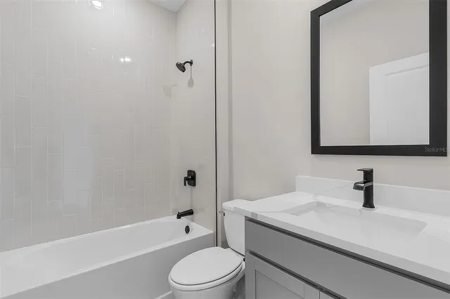 a bathroom with a granite countertop sink a toilet and bathtub