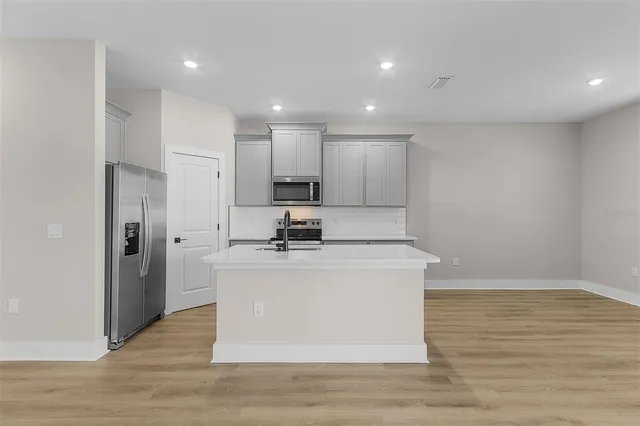 a view of kitchen with stainless steel appliances wooden floor large window and wooden floor