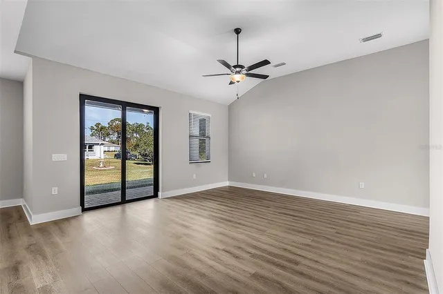 a view of an empty room with a window and wooden floor