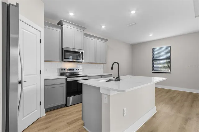 a kitchen with a sink stainless steel appliances and white cabinets