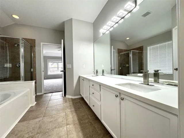 a large bathroom with a granite countertop double vanity sink a mirror and a bathtub