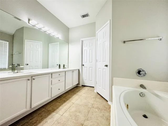 a bathroom with a bathtub a sink and a large mirror