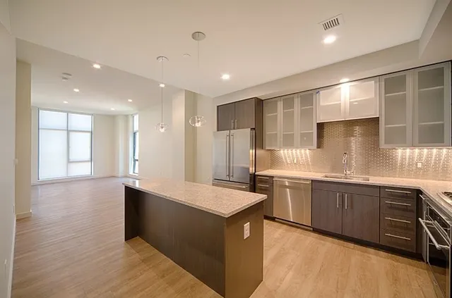 a large kitchen with stainless steel appliances granite countertop a large counter top a sink and a refrigerator