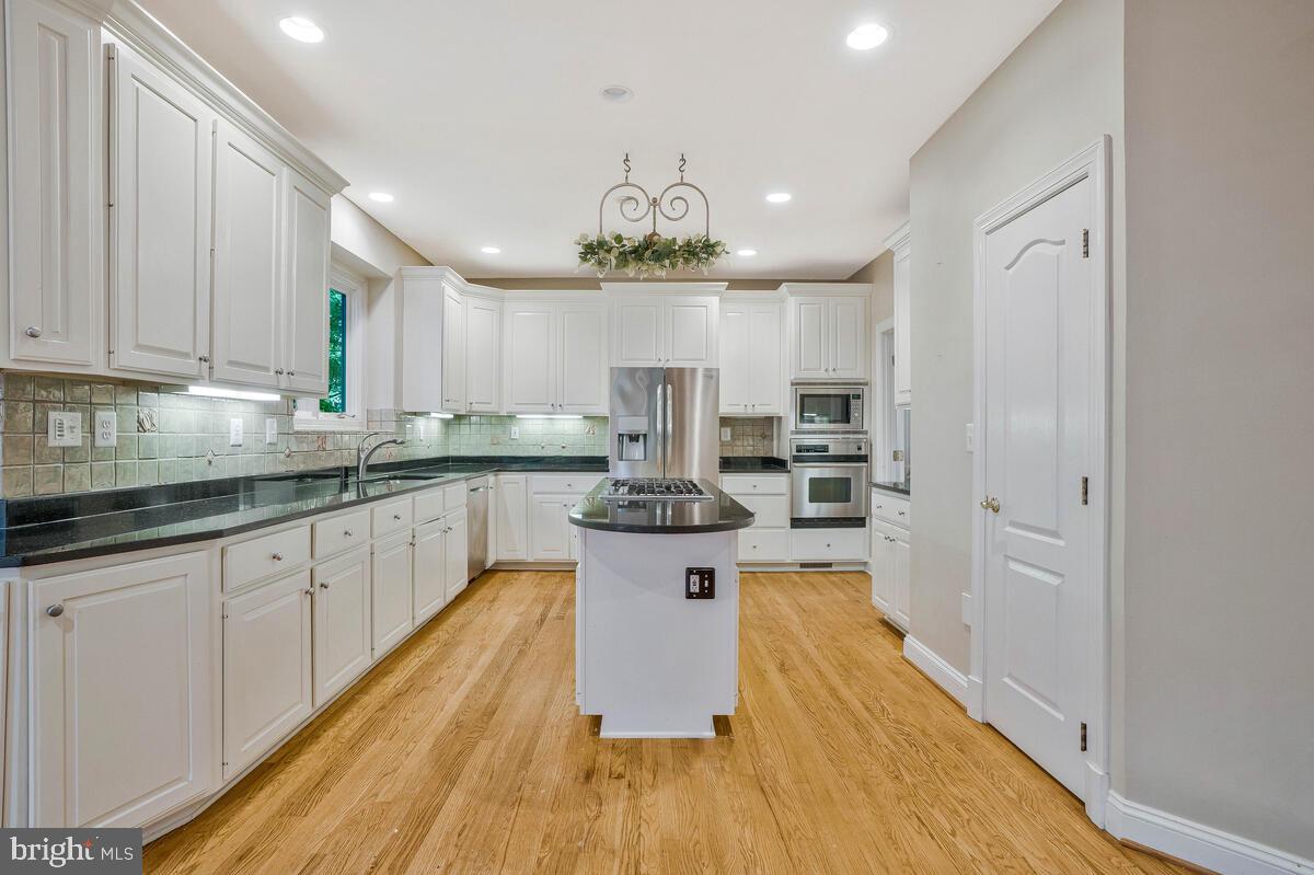 502 Seneca Knoll Court Great Falls, VA 22066 - Photo 18 of 56 a kitchen with stainless steel appliances granite countertop a sink dishwasher a refrigerator and white cabinets with wooden floor