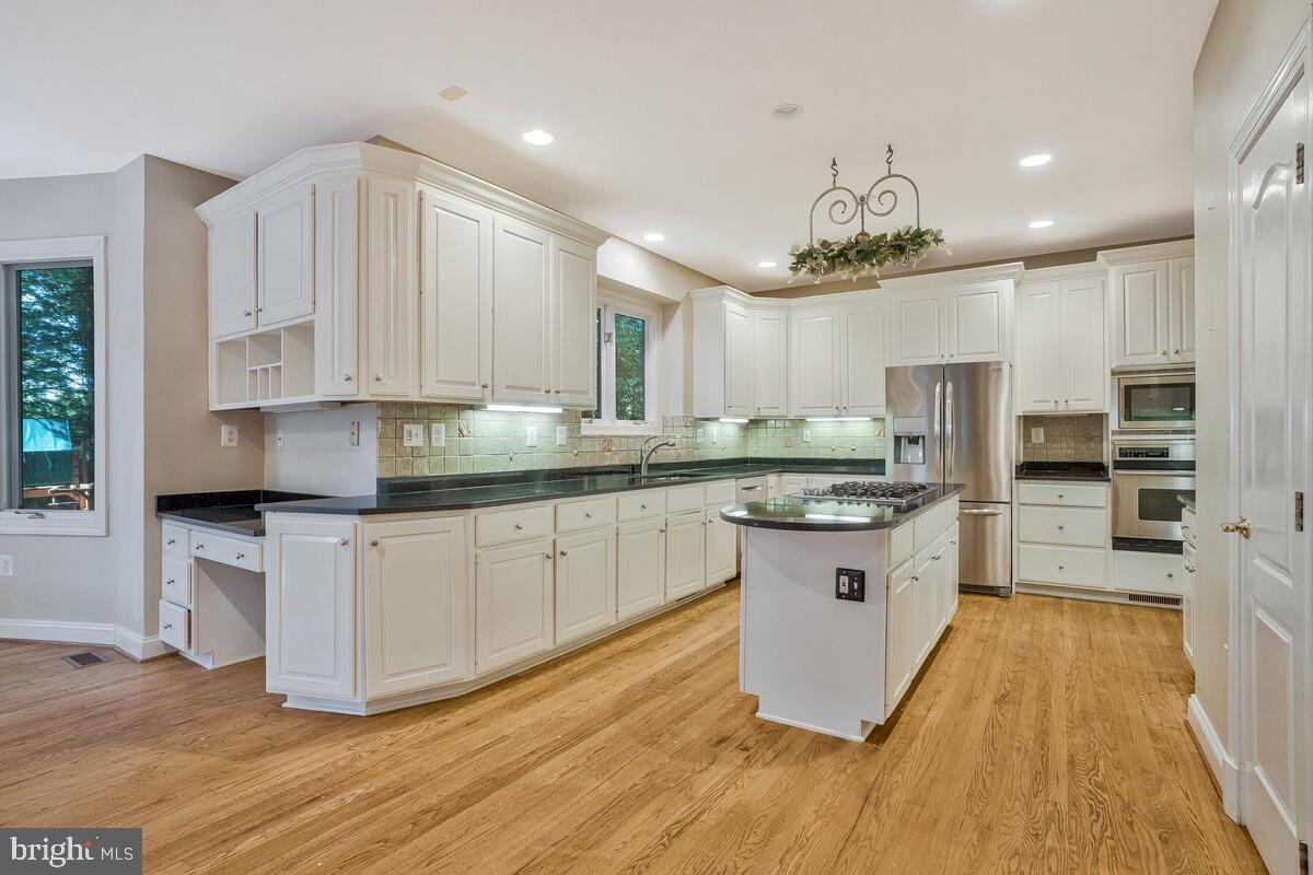 502 Seneca Knoll Court Great Falls, VA 22066 - Photo 19 of 56 a kitchen with stainless steel appliances granite countertop a sink cabinets and wooden floor