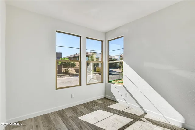 a view of an empty room with wooden floor and a window