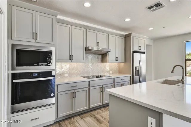 a kitchen with stainless steel appliances granite countertop a kitchen island hardwood floor sink and stove