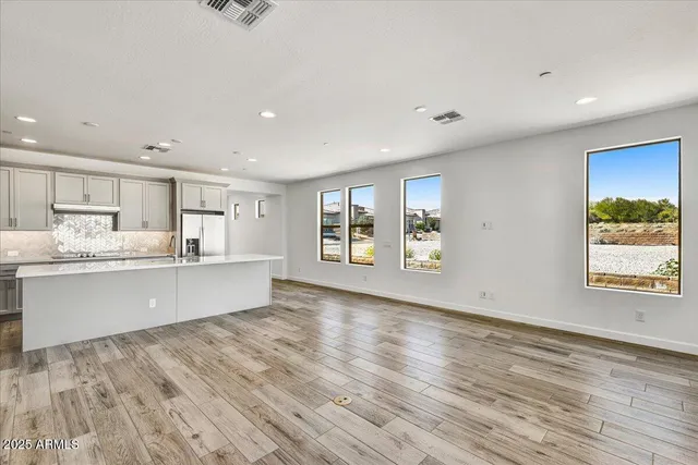 a large kitchen with stainless steel appliances granite countertop a large counter top and a wooden floors
