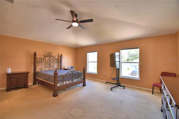 a spacious bedroom with a bed a dresser and a chandelier