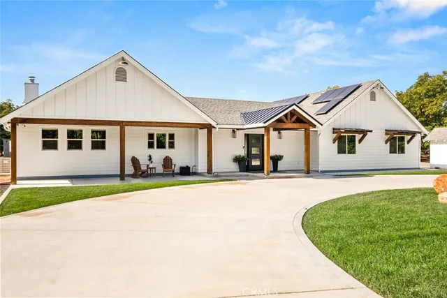 a view of a white house with a big yard and potted plants