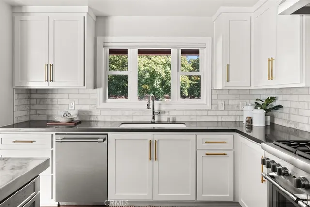 a kitchen with granite countertop white cabinets and a window