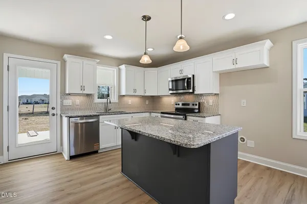 a kitchen with stainless steel appliances kitchen island granite countertop a stove a sink and a wooden floor