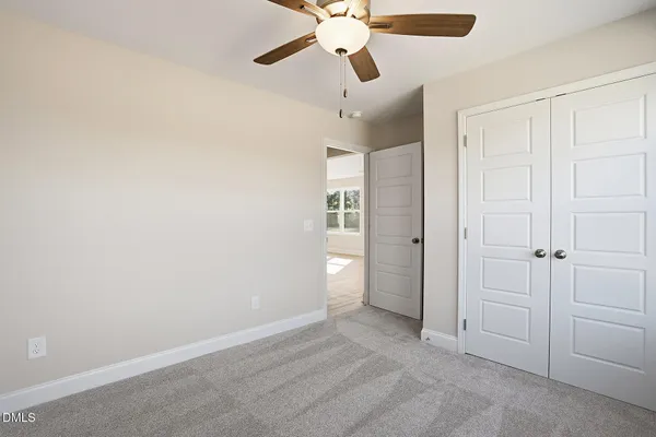 an empty room with closet and a chandelier fan
