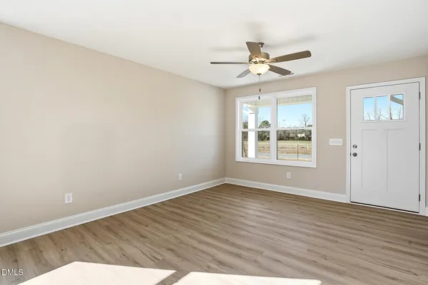 a view of an empty room with wooden floor and a window