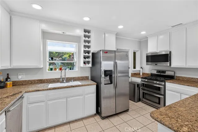 a kitchen with stainless steel appliances granite countertop a refrigerator a sink a stove a microwave a counter top space and cabinets