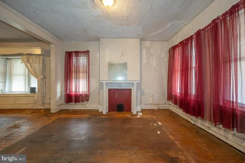 an empty room with windows a fireplace and painted walls