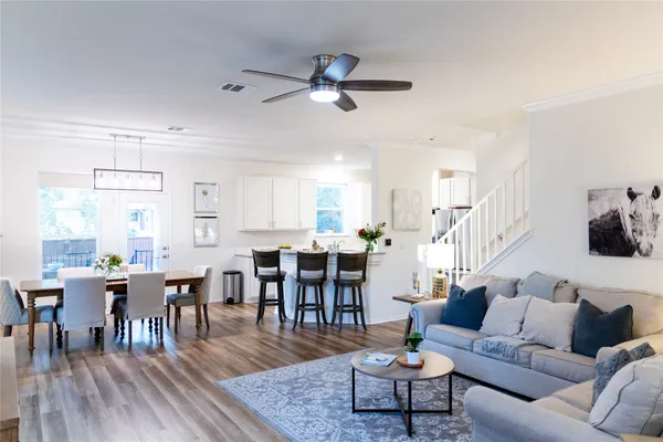 a living room with furniture kitchen view and a wooden floor
