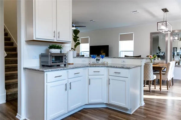 a kitchen with granite countertop white cabinets white appliances a sink and wooden floor