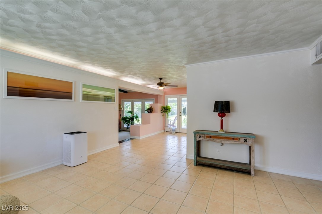 4087 Pleasant Road Las Vegas, NV 89108 - Photo 12 of 74 Empty room with french doors, light tile patterned floors, a ceiling fan, ornamental molding, and a textured ceiling