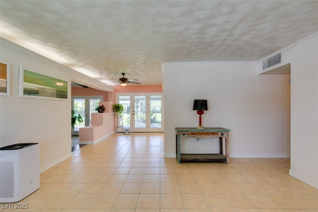 4087 Pleasant Road Las Vegas, NV 89108 - Photo 18 of 74 Empty room featuring french doors, light tile patterned floors, a ceiling fan, and crown molding