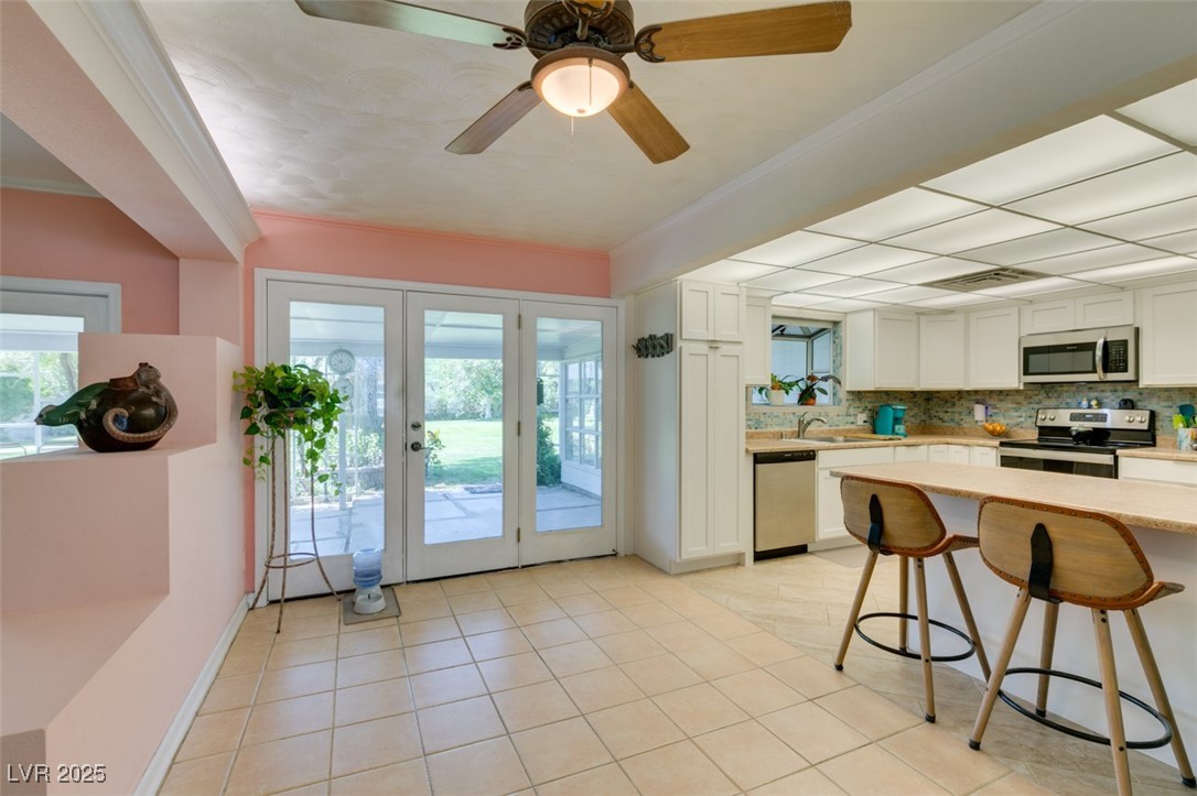 4087 Pleasant Road Las Vegas, NV 89108 - Photo 19 of 74 Kitchen featuring decorative backsplash, light countertops, french doors, white cabinets, and ornamental molding