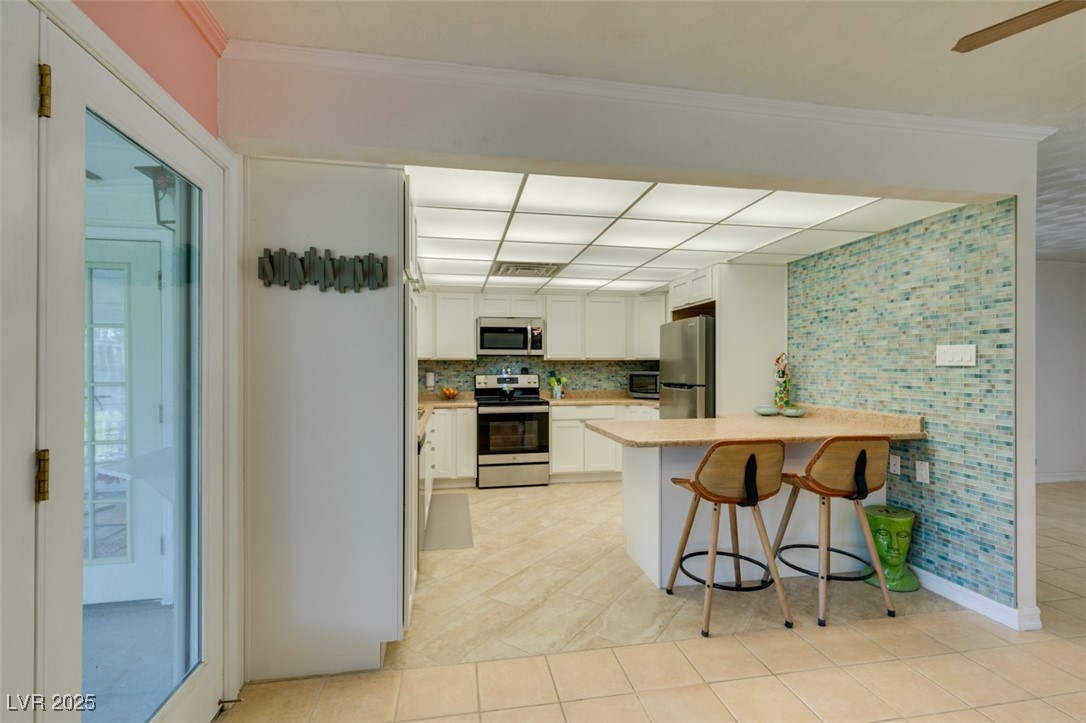 4087 Pleasant Road Las Vegas, NV 89108 - Photo 23 of 74 Kitchen with tasteful backsplash, stainless steel appliances, a peninsula, light countertops, and white cabinetry