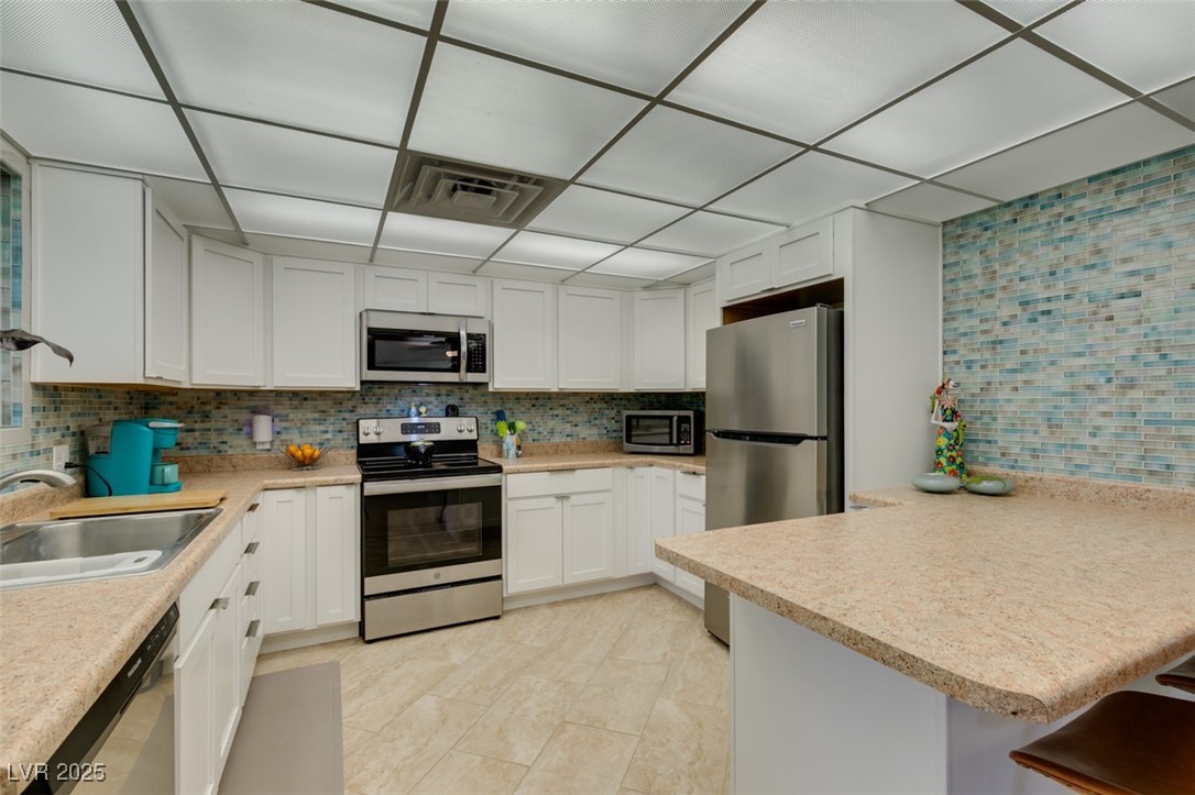 4087 Pleasant Road Las Vegas, NV 89108 - Photo 26 of 74 Kitchen featuring tasteful backsplash, appliances with stainless steel finishes, a peninsula, and light countertops