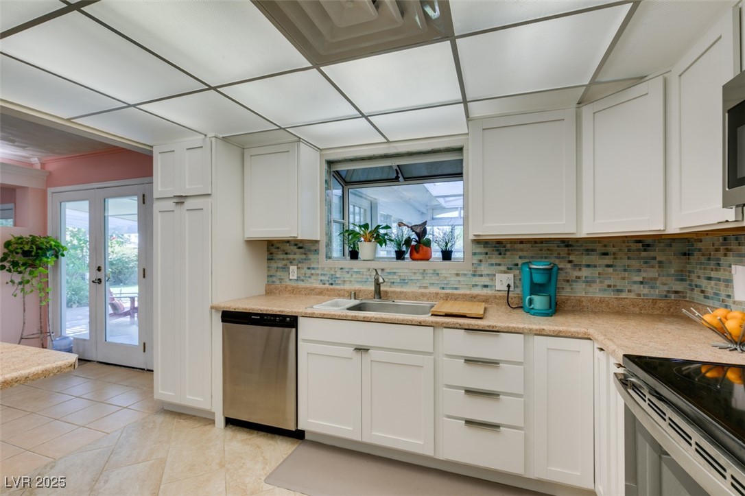 4087 Pleasant Road Las Vegas, NV 89108 - Photo 28 of 74 Kitchen with appliances with stainless steel finishes, french doors, light countertops, backsplash, and light tile patterned flooring