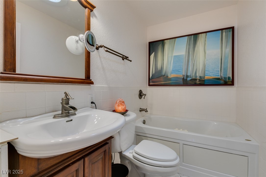4087 Pleasant Road Las Vegas, NV 89108 - Photo 49 of 74 Bathroom with a bath, vanity, tile walls, a textured wall, and a wainscoted wall