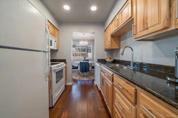 a kitchen with granite countertop a sink stove refrigerator and cabinets