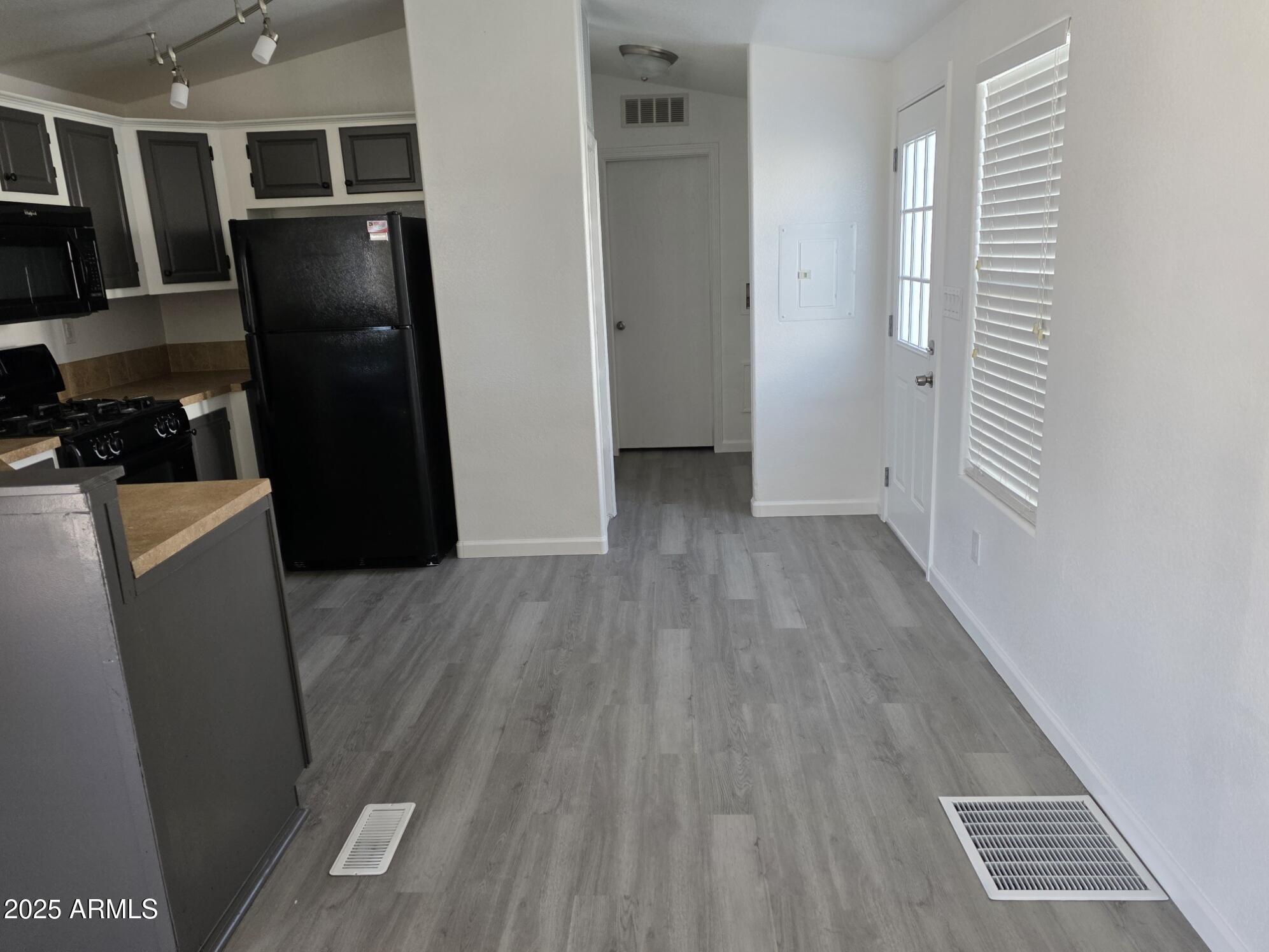 7807 East Main Street, Unit C6 Mesa, AZ 85207 - Photo 7 of 32 a view of a refrigerator in kitchen and an empty room with wooden floor