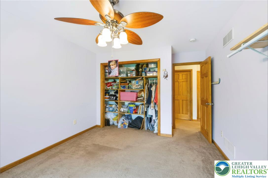 6970 Silver Crest Road Nazareth, PA 18064 - Photo 25 of 35 A well-lit bedroom features plush carpeting, a functional closet, and a vaulted ceiling with a fan.