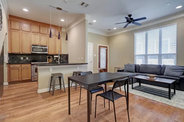 a kitchen with stainless steel appliances kitchen island granite countertop a stove a sink a dining table and chairs with wooden floor