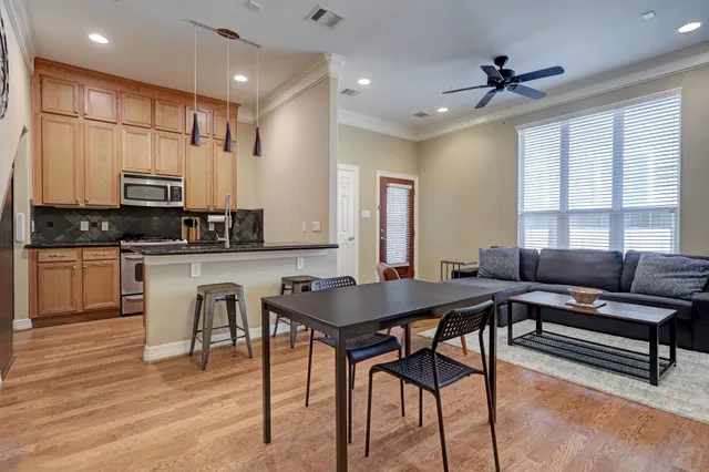 a kitchen with stainless steel appliances kitchen island granite countertop a stove a sink a dining table and chairs with wooden floor