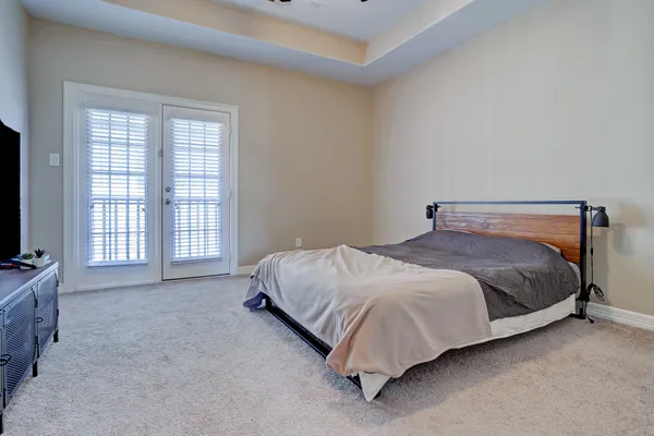 a bedroom with a bed flat screen tv and windows