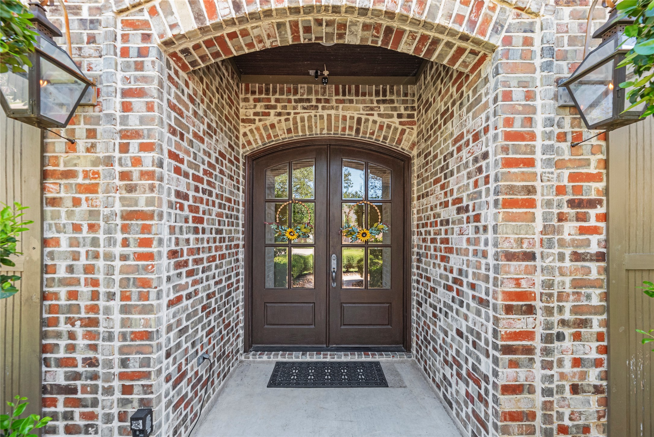 3550 Windrose Drive Beaumont, TX 77706 - Photo 11 of 50 Charming brick archway frames the stately double doors with glass panels and wreath décor. Gas lantern-style sconces add a classic touch to the front entry.