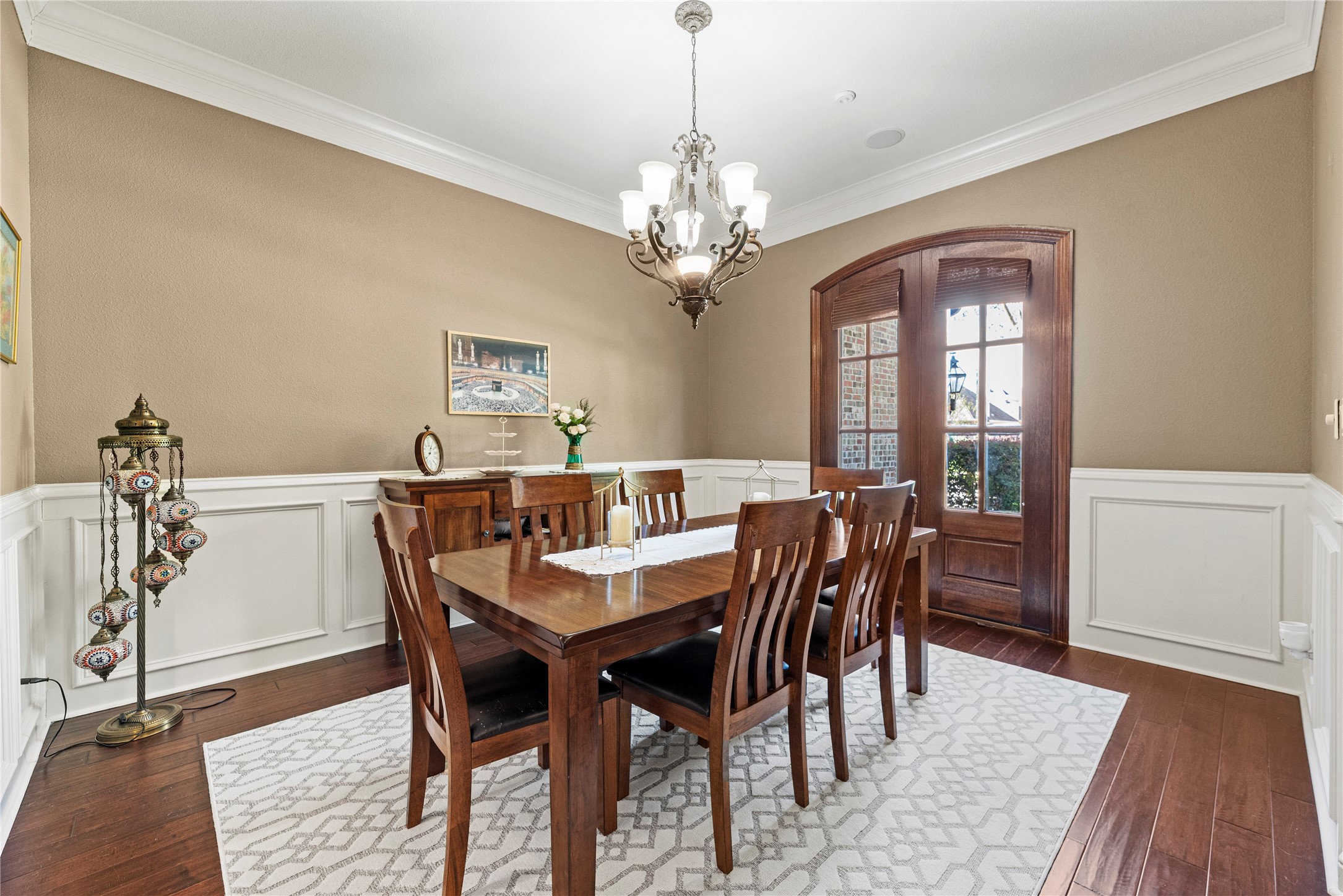 3550 Windrose Drive Beaumont, TX 77706 - Photo 15 of 50 Elegant formal dining area featuring detailed wall paneling, chandelier lighting, and beautiful ornamental French doors that frame the front elevation. A warm, refined setting for gatherings and holiday entertaining.