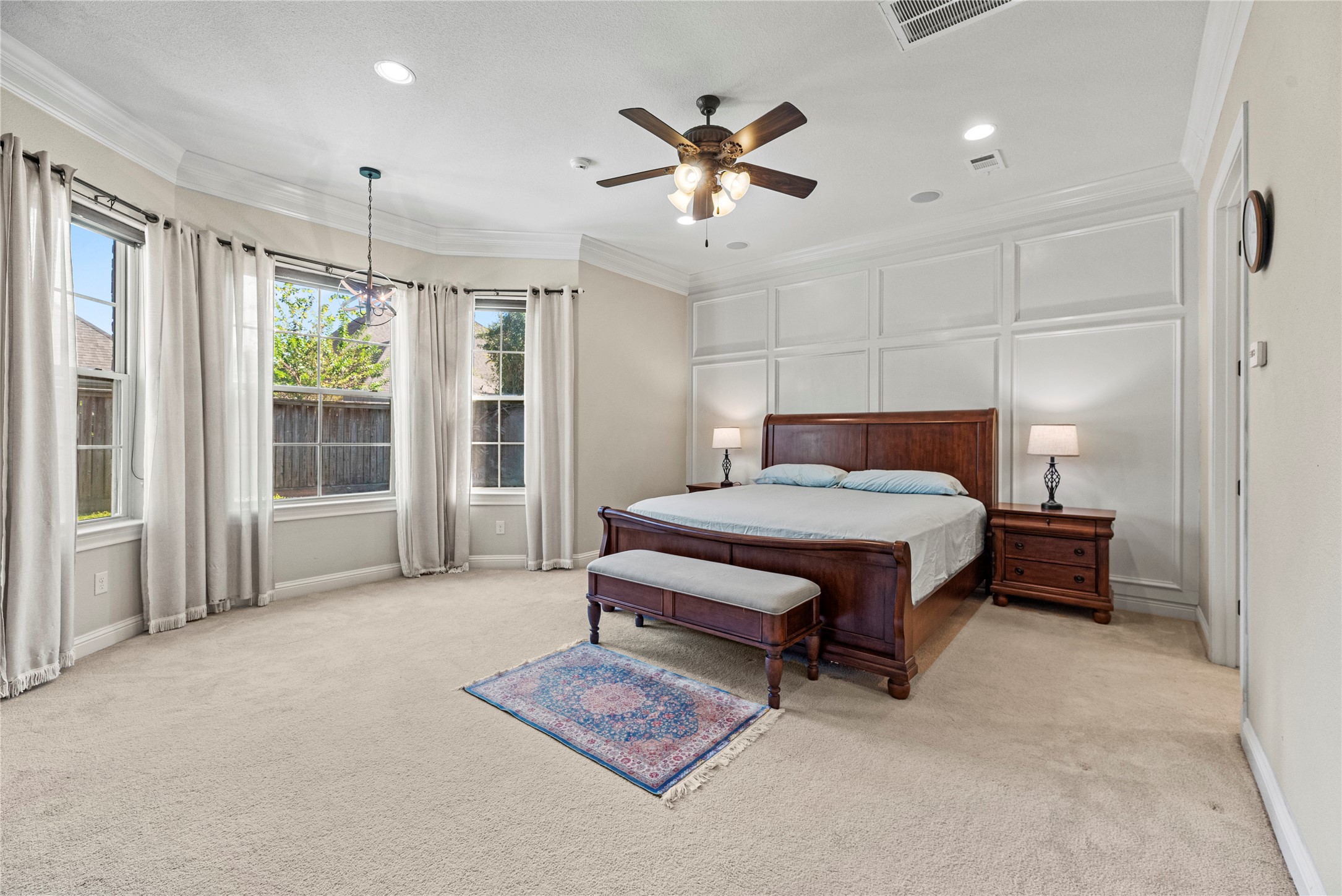 3550 Windrose Drive Beaumont, TX 77706 - Photo 25 of 50 Expansive primary suite featuring a sophisticated accent wall, crown molding, and a serene bay window sitting area overlooking the backyard. Plush carpeting creates a peaceful retreat filled with natural light.