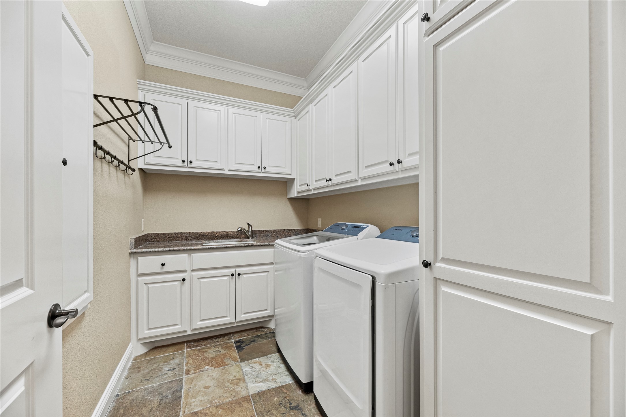 3550 Windrose Drive Beaumont, TX 77706 - Photo 33 of 50 Oversized laundry room featuring abundant cabinetry, granite countertop with sink, and rich multicolor slate tile flooring — showcasing earthy browns, golds, and charcoal tones that add warmth and natural character. Designed for both function and timeless style.