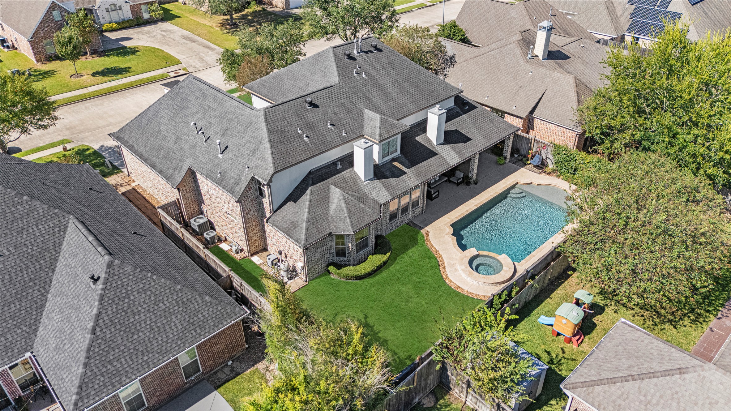 3550 Windrose Drive Beaumont, TX 77706 - Photo 47 of 50 A stunning view of the private backyard oasis featuring a sparkling pool with attached spa, lush lawn, and covered patio — perfect for entertaining or relaxing year-round.