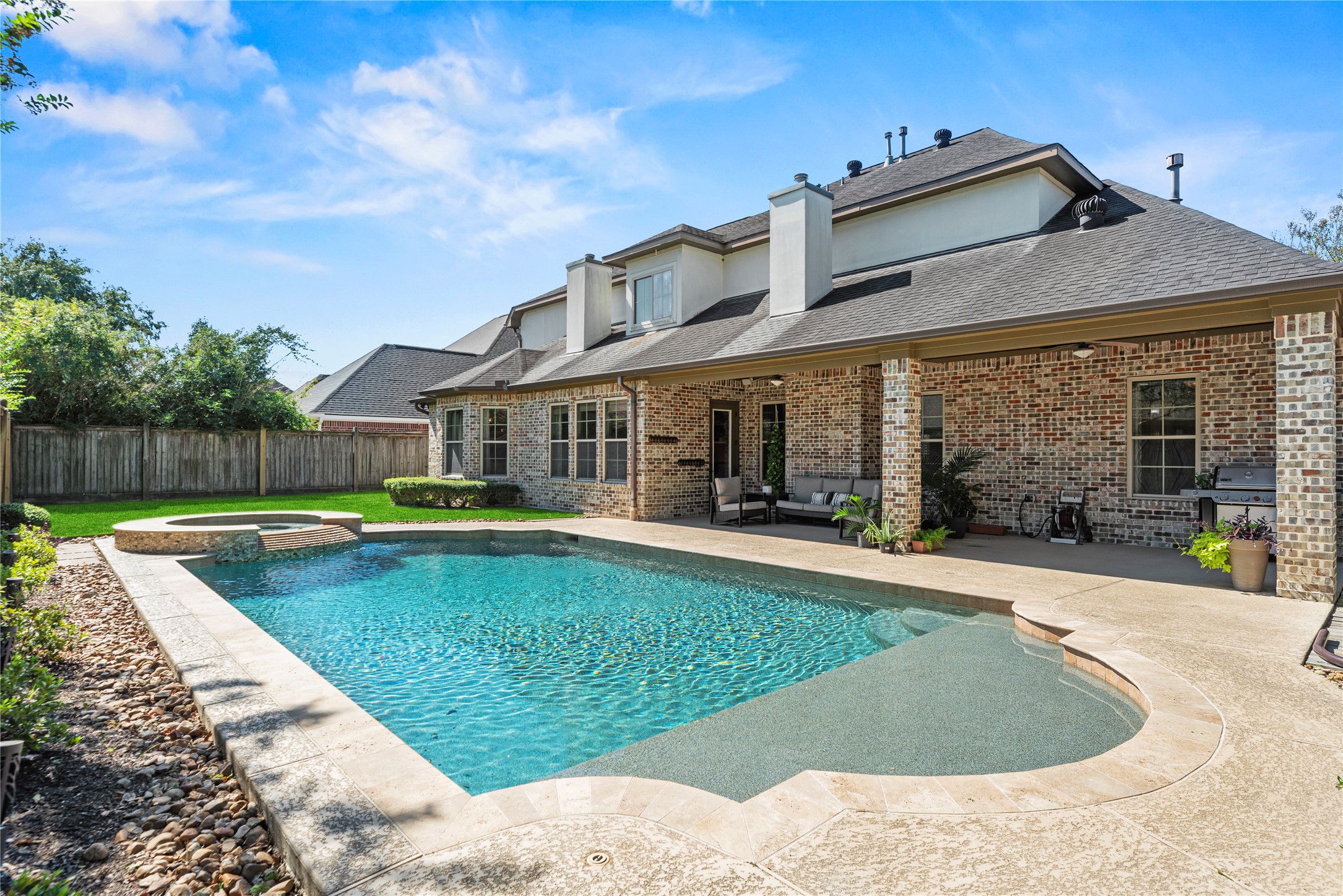 3550 Windrose Drive Beaumont, TX 77706 - Photo 7 of 50 Impressive rear view of the home showcasing its extended covered patio, brick exterior, and serene pool setting — a true outdoor retreat.