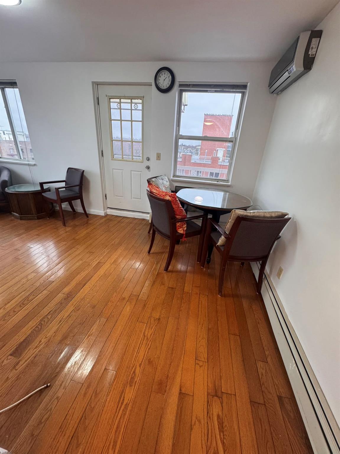 136-16 31st Road, Unit 8A Queens, NY 11354 - Photo 2 of 16 Dining room featuring hardwood / wood-style floors, a baseboard radiator, and a wall unit AC
