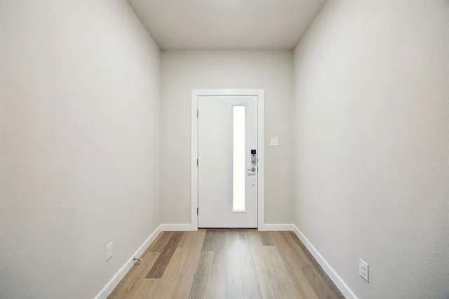 a view of an empty room with wooden floor and closet