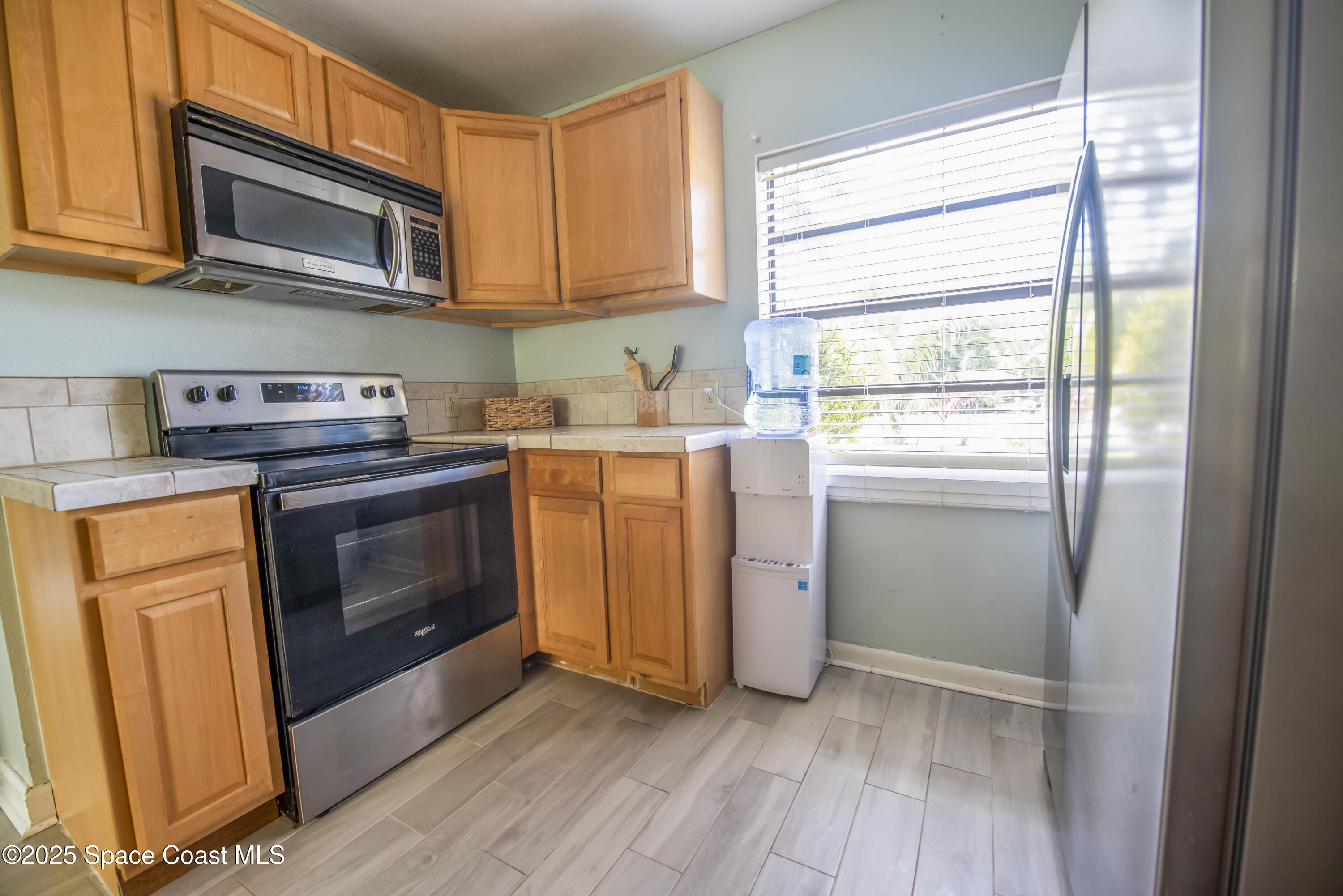 142 Atlantic Avenue Indialantic, FL 32903 - Photo 11 of 28 a kitchen with granite countertop wooden cabinets stainless steel appliances and a window