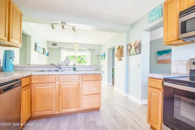 a kitchen with stainless steel appliances granite countertop a refrigerator a sink dishwasher and white cabinets with wooden floor