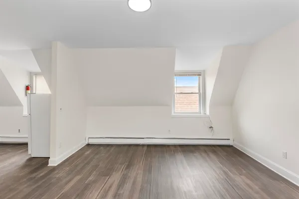 an empty room with wooden floor and window
