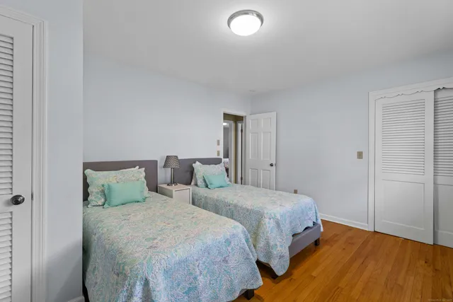 a bedroom with two beds and wooden floor
